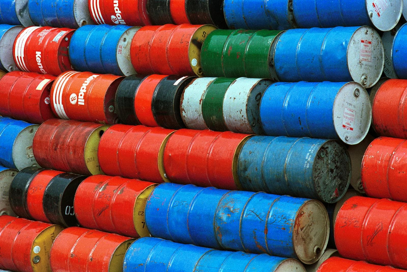 Stabel av fargerike industrifat i metall i rødt, blått, grønt og hvitt